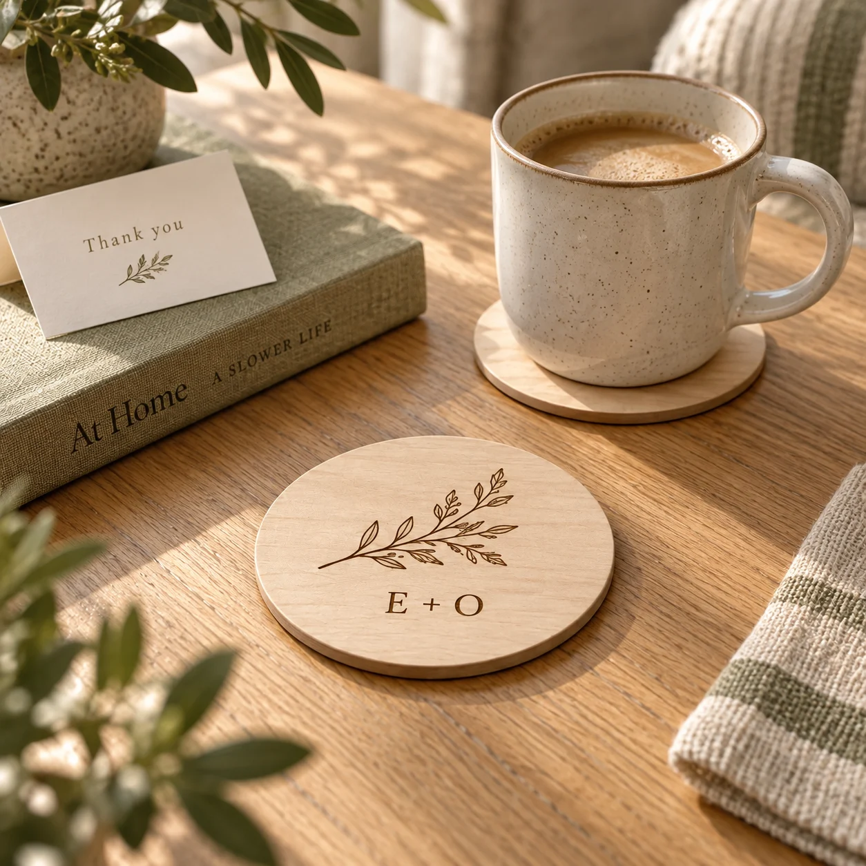 Thin botanical birch coasters beside a morning coffee and a closed linen book