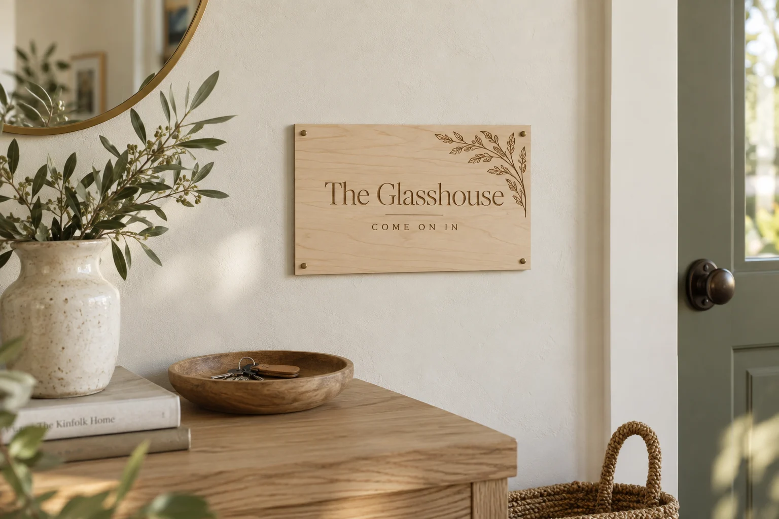 An engraved wooden Glasshouse sign beside the front door, above an oak console with a bowl of keys